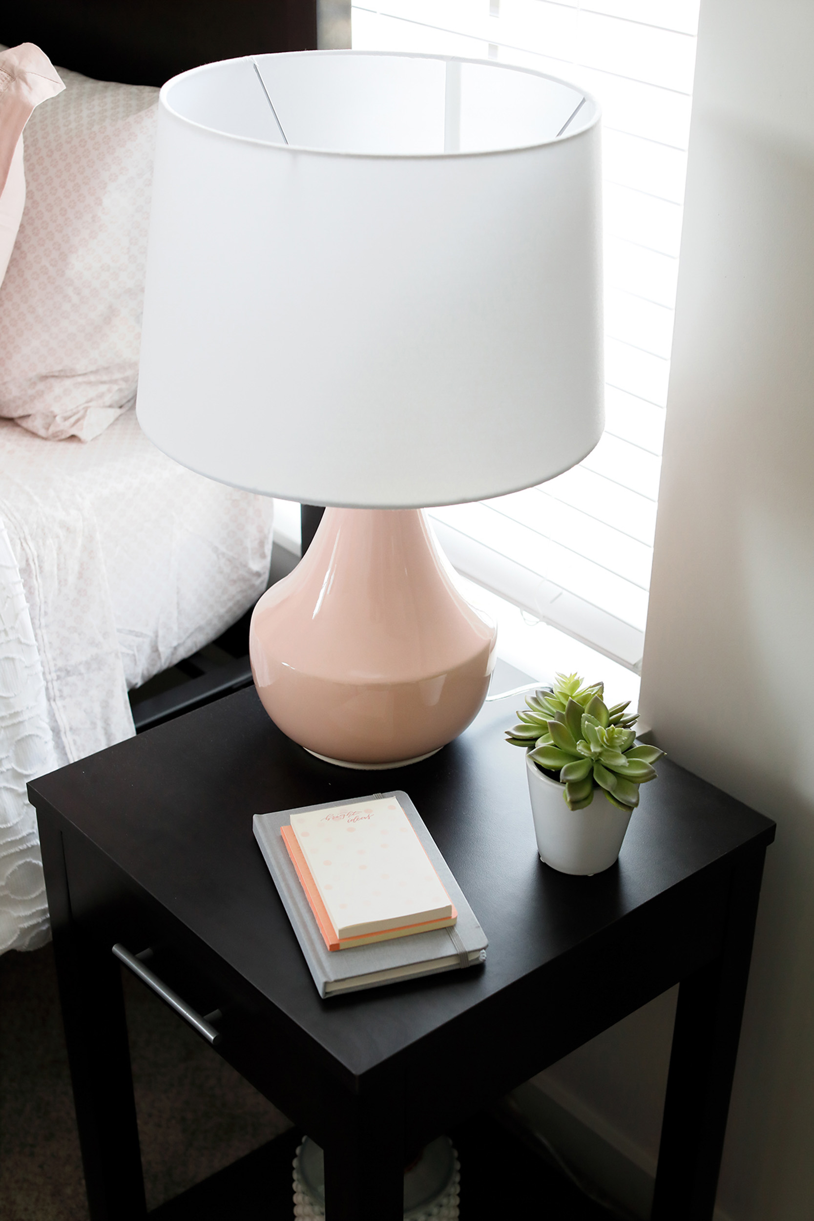 Bedside table with lamp notebooks and succulent