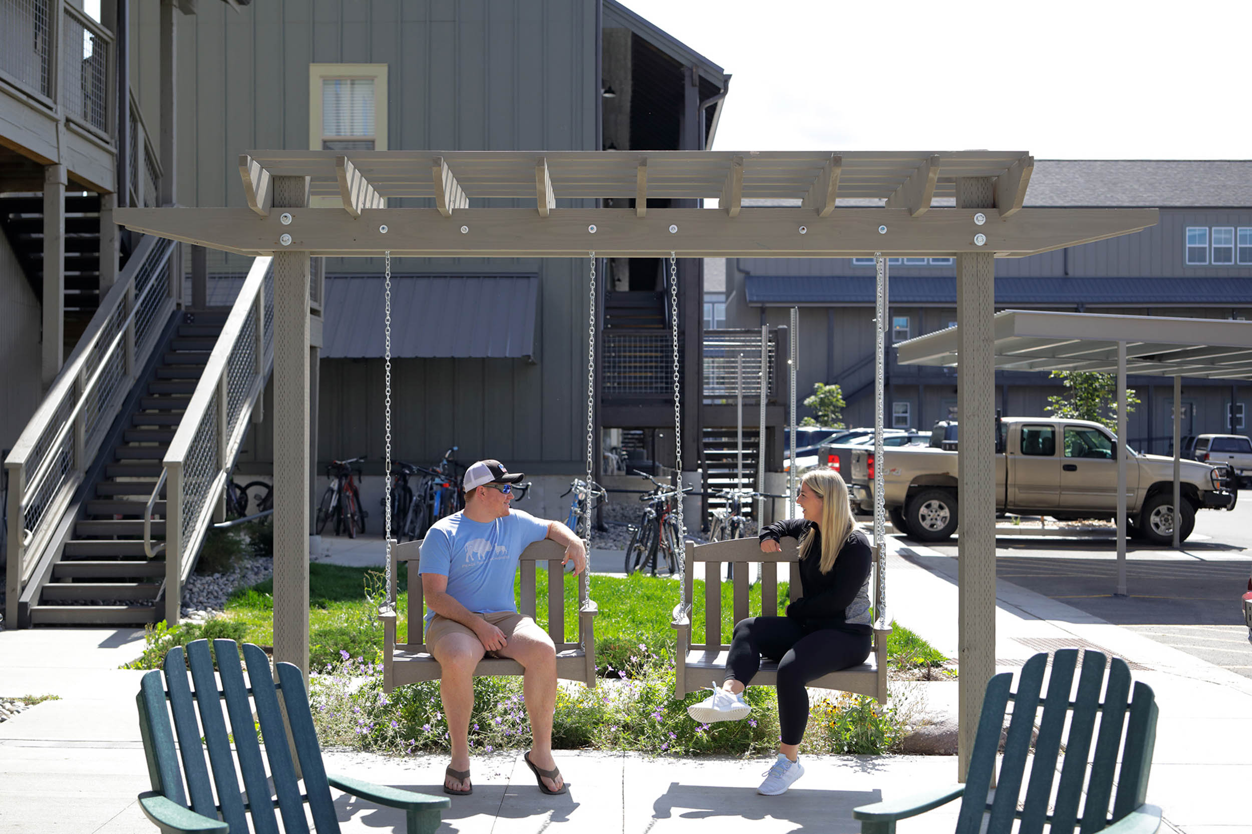 Friends sitting on bench swings under pergola