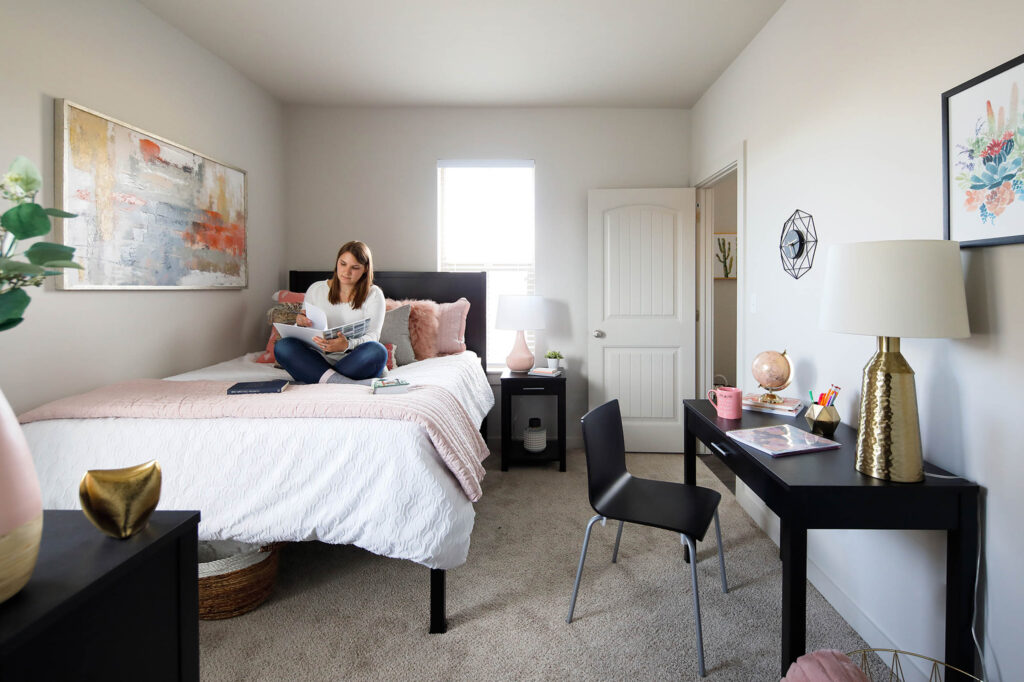 Woman sitting on bed studying in apartment bedroom